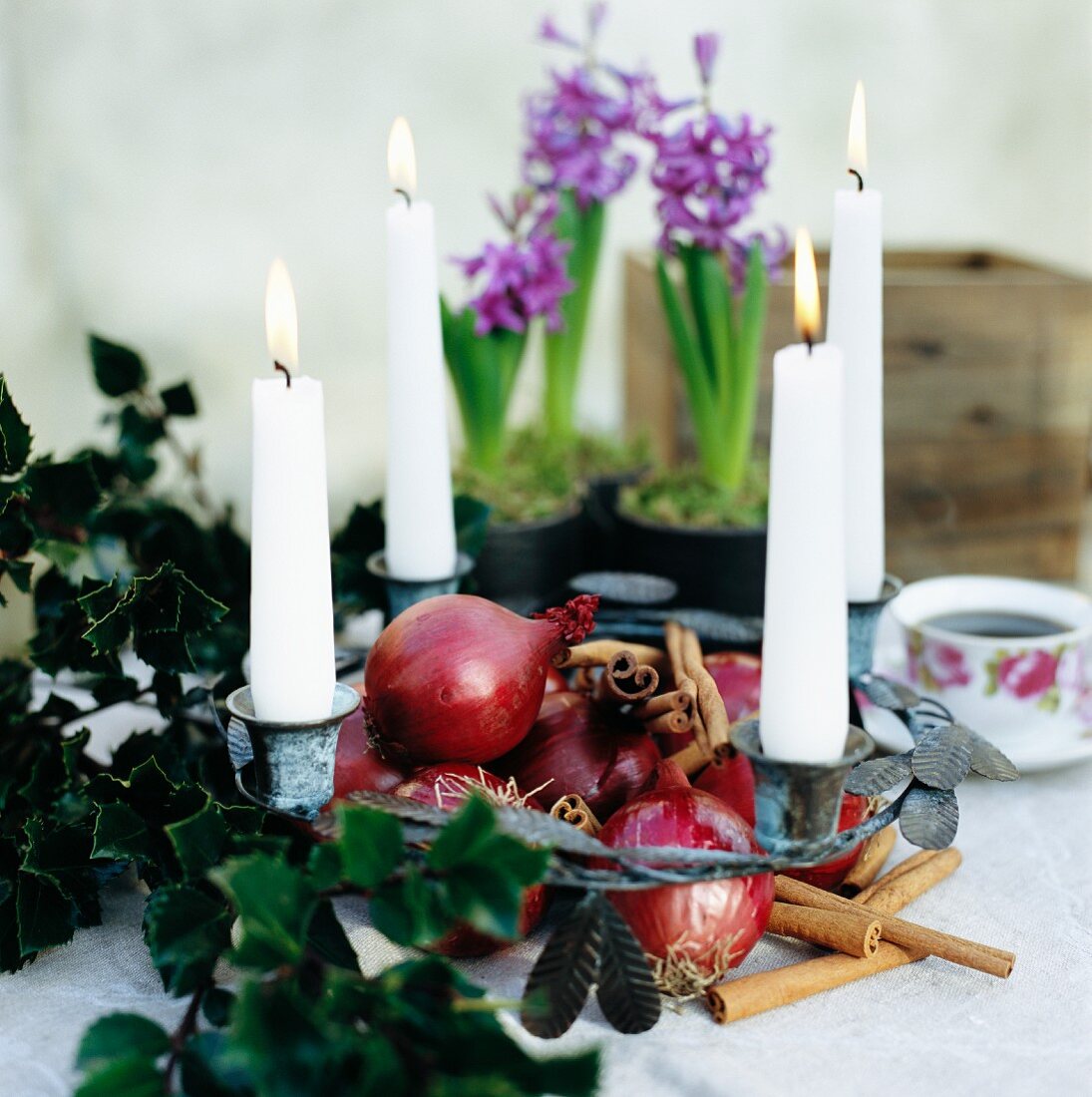 Advent wreath decorated with four burning candles, red onions and cinnamon sticks