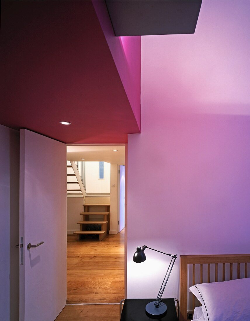 Schlafraum mit teilweise violett getönter Decke über offenstehender Tür und Blick auf Treppe