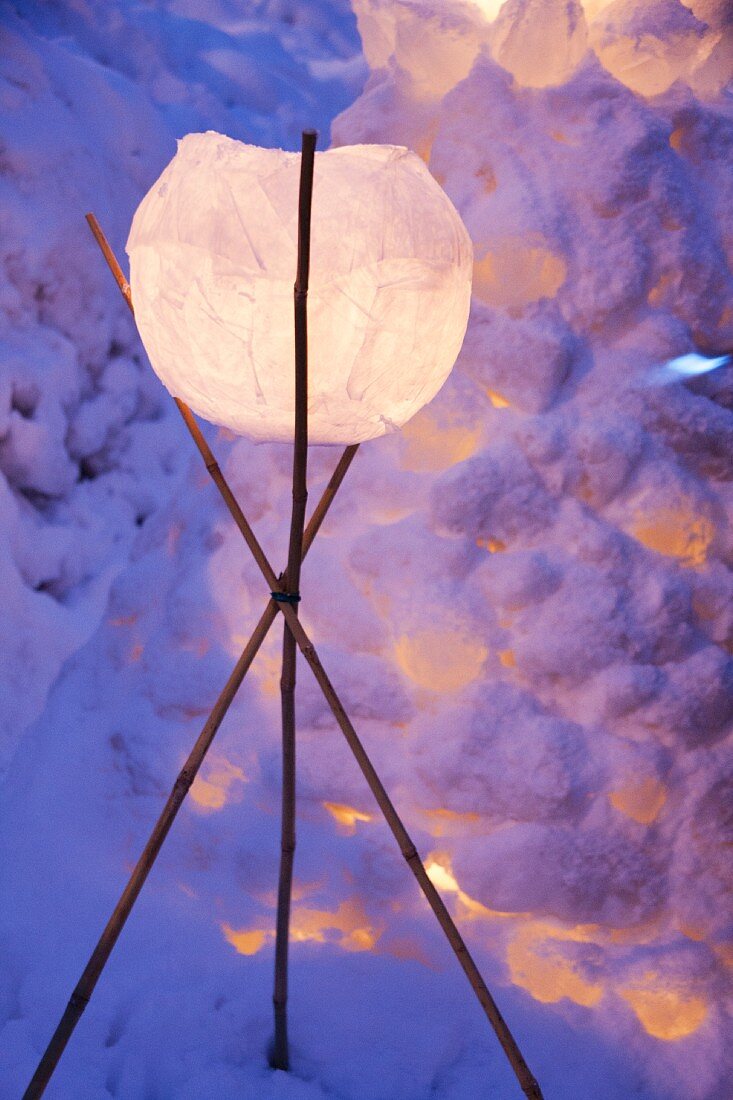 Lantern on tripod of sticks in snow