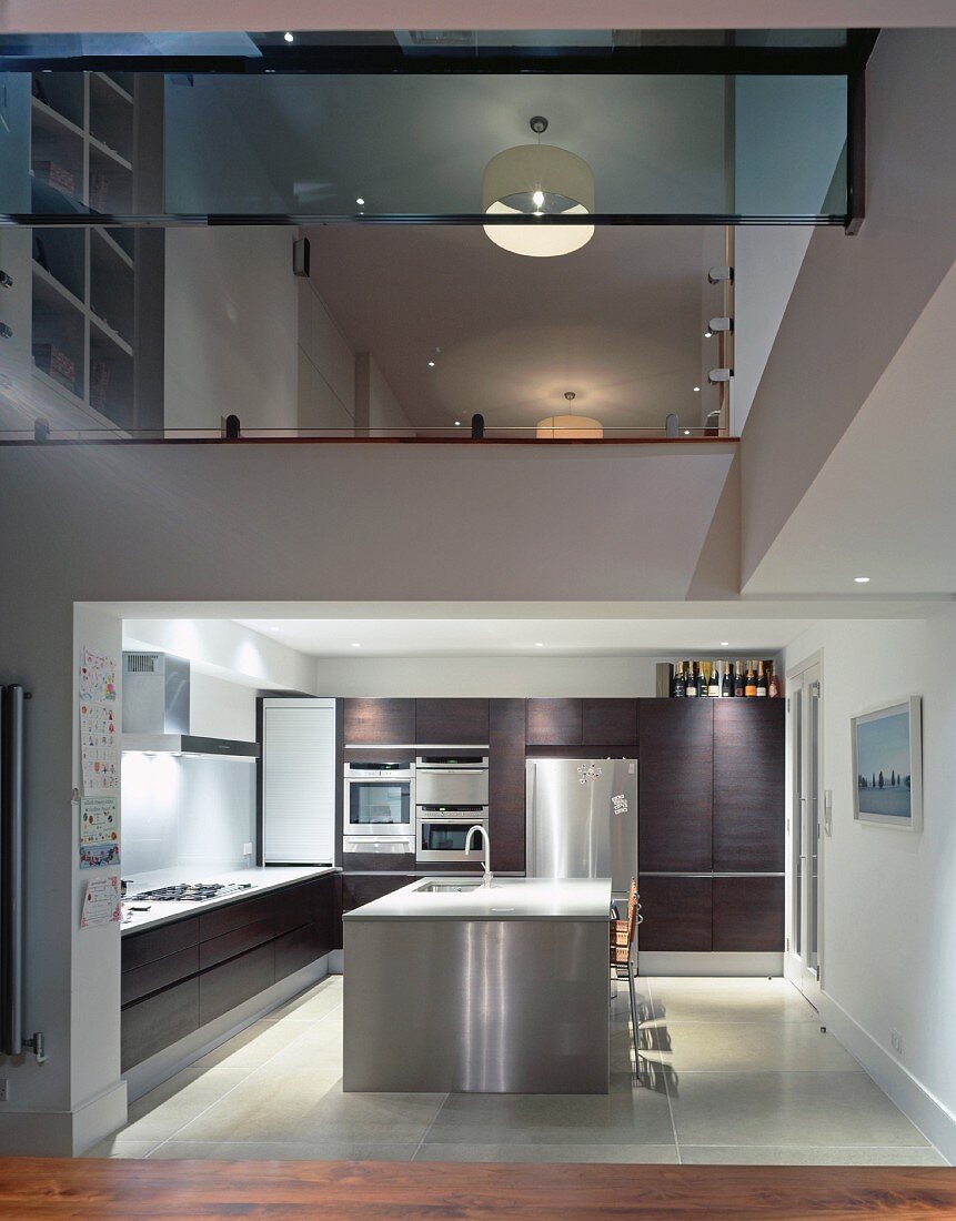 View into kitchen with stainless steel island and upper storey