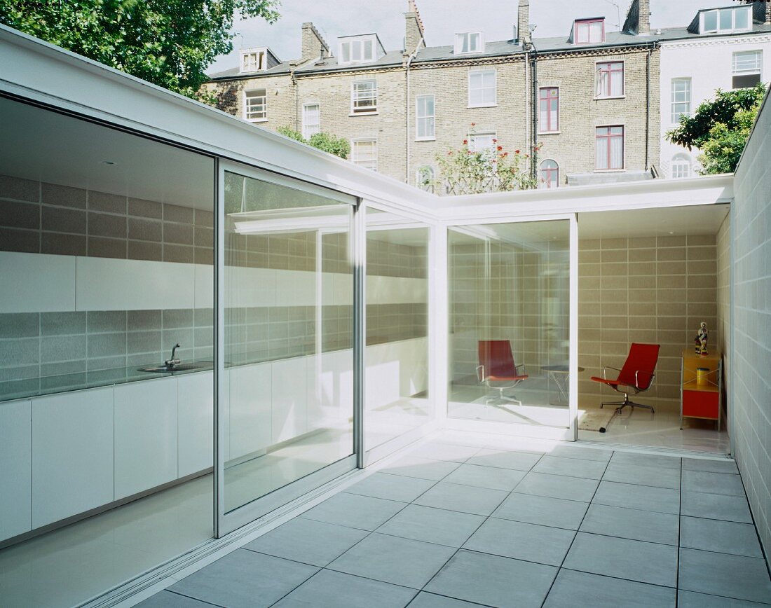 Courtyard with white tiled floor and view of interior through open sliding terrace doors