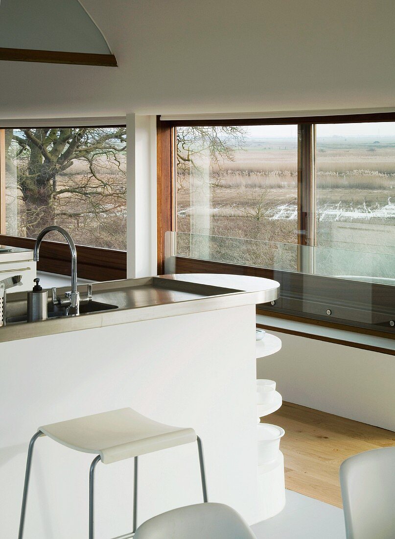 Küchenblock mit Arbeitsplatte aus Edelstahl vor Fensterfront im modernen Wohnhaus