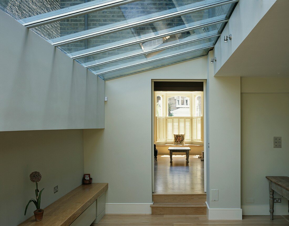 Wohnraum im modernen Anbau mit Glasdach und Blick durch offenen Durchgang