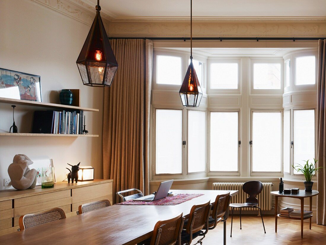 Langer Holztisch mit Stühlen aus Bauhauszeit vor Erker im klassischem Stil
