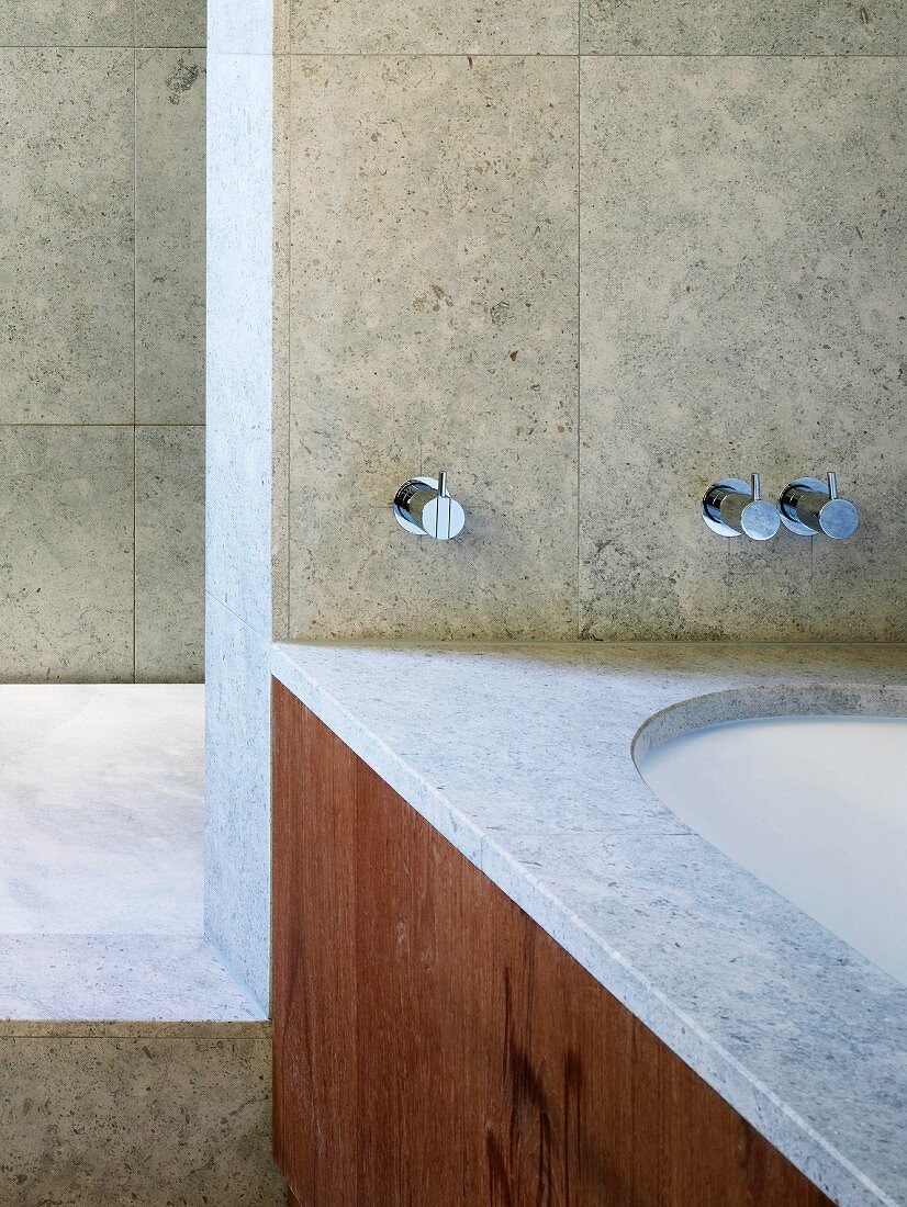 Detail of bathroom with marble cladding on walls and on rim of bathtub