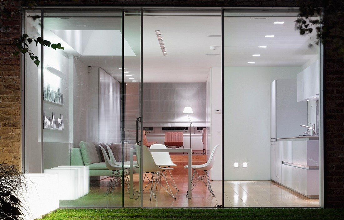 Floor-to-ceiling glass wall with view of dining area in illuminated interior