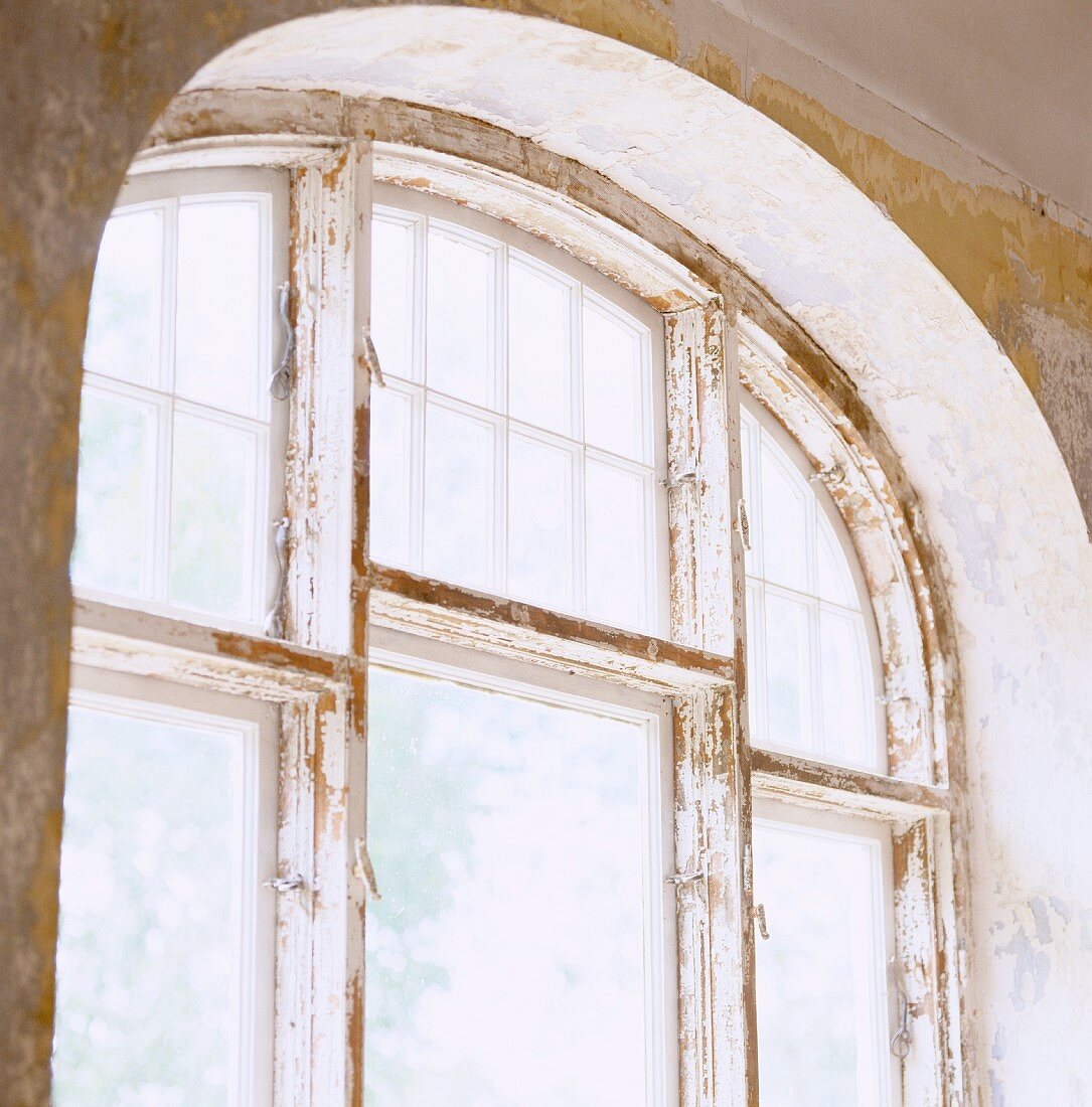 Renovierungsarbeiten an Fensterrahmen mit Rundbogen