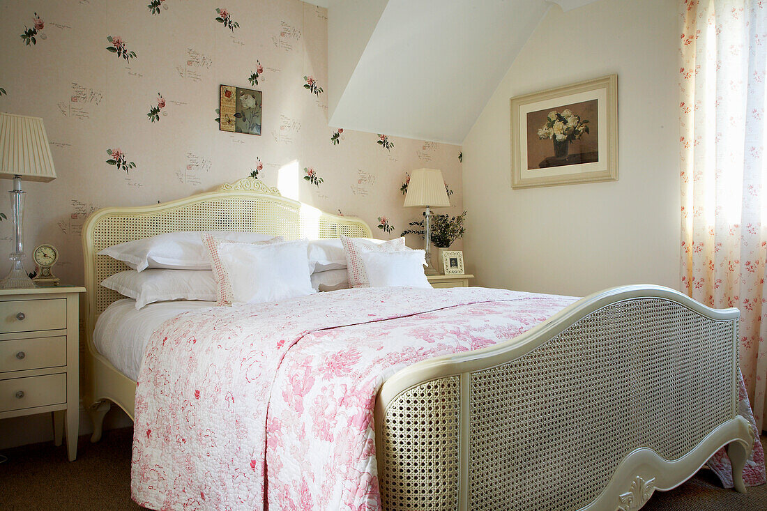 Country-style bedroom with floral bed linen and rattan bed frame
