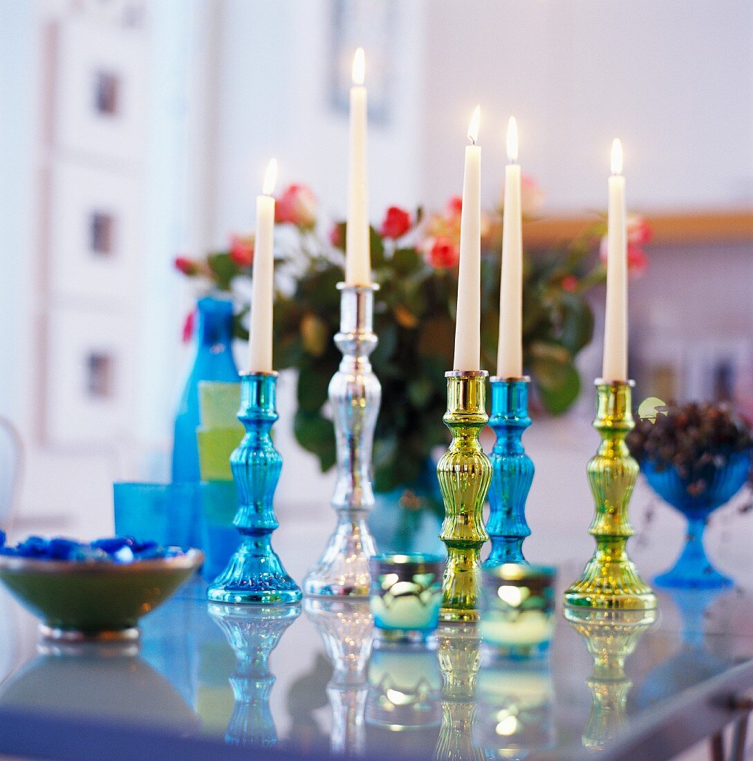 Colourful candlesticks on table with burning white candles
