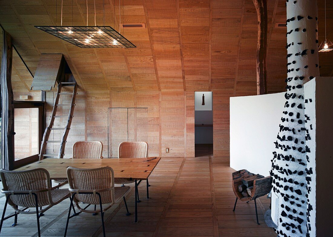 Essplatz mit Rattanstühlen im holzverkleideten Wohnraum im Designerstil