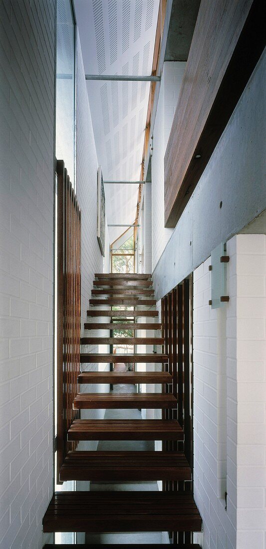 Modern staircase with wooden treads in narrow stairwell