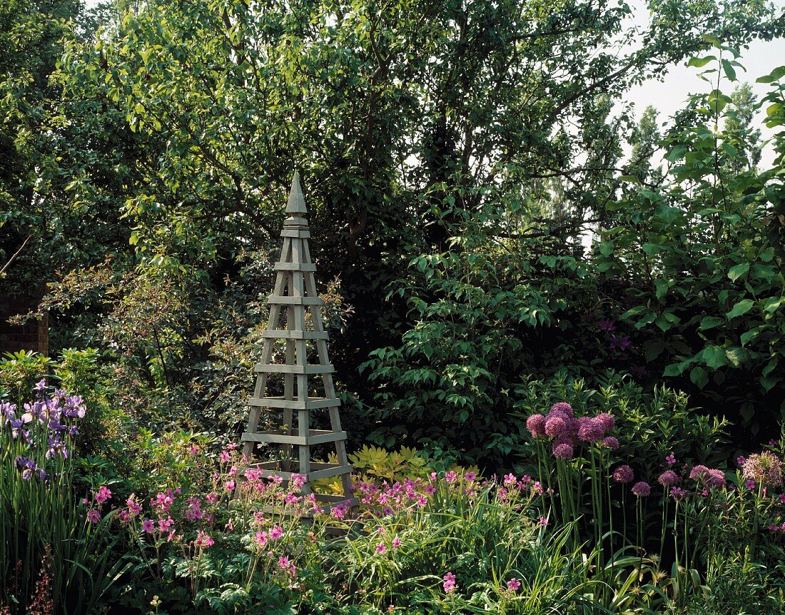 Rank-Pyramide aus Holz vor Bäumen in Bauerngarten