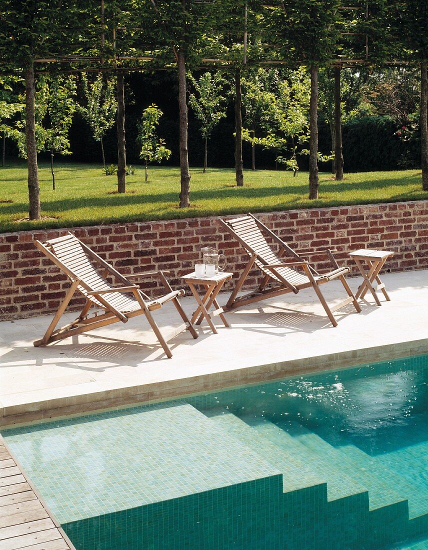 Liegestühle an Pool mit gemauerter Treppe und englischer Rasen mit Bäumen