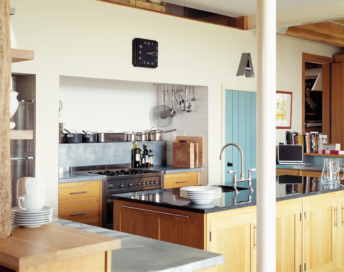 Moderne Landhausküche mit Holzfronten und schwarzer Steinplatte auf dem Spülenblock