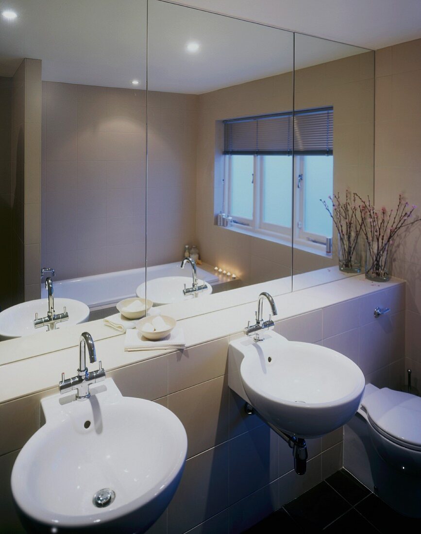 Round washbasins beneath large mirror in modern bathroom