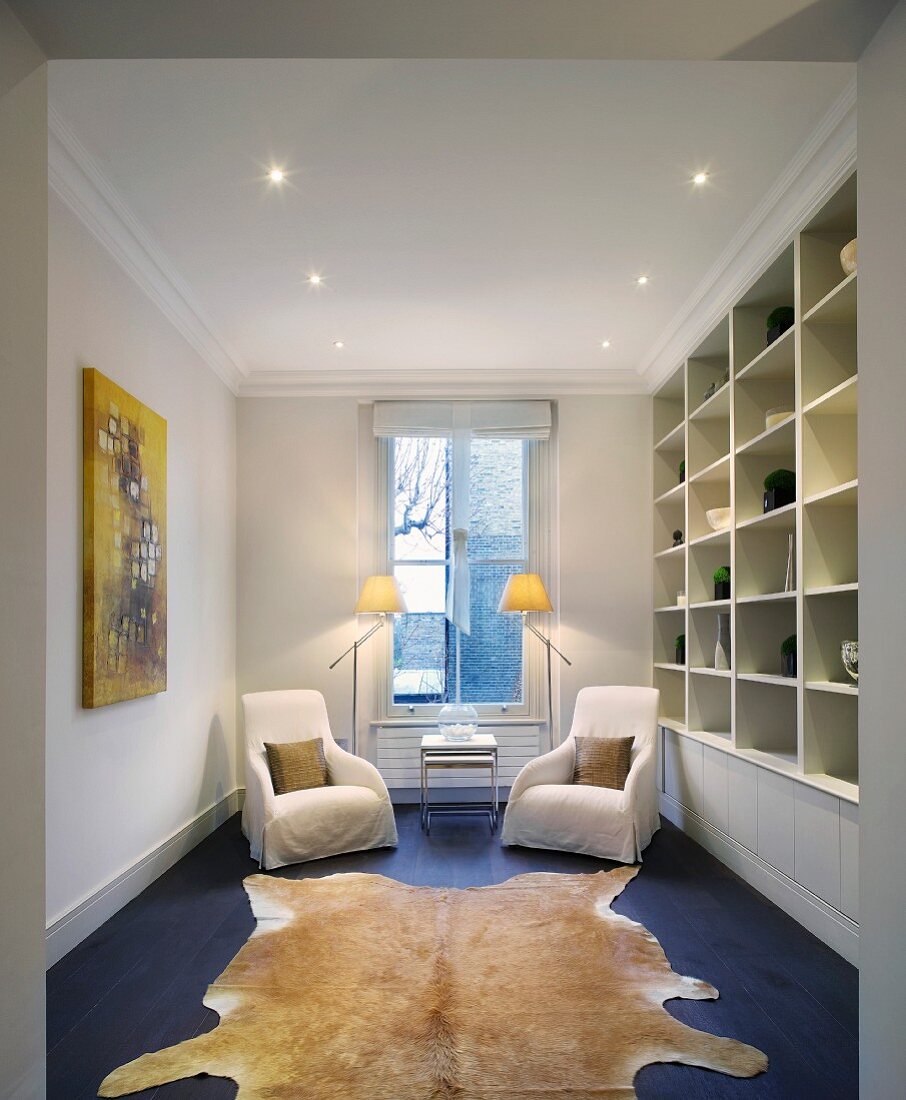 Fitted shelving and seating area in front of window in narrow room