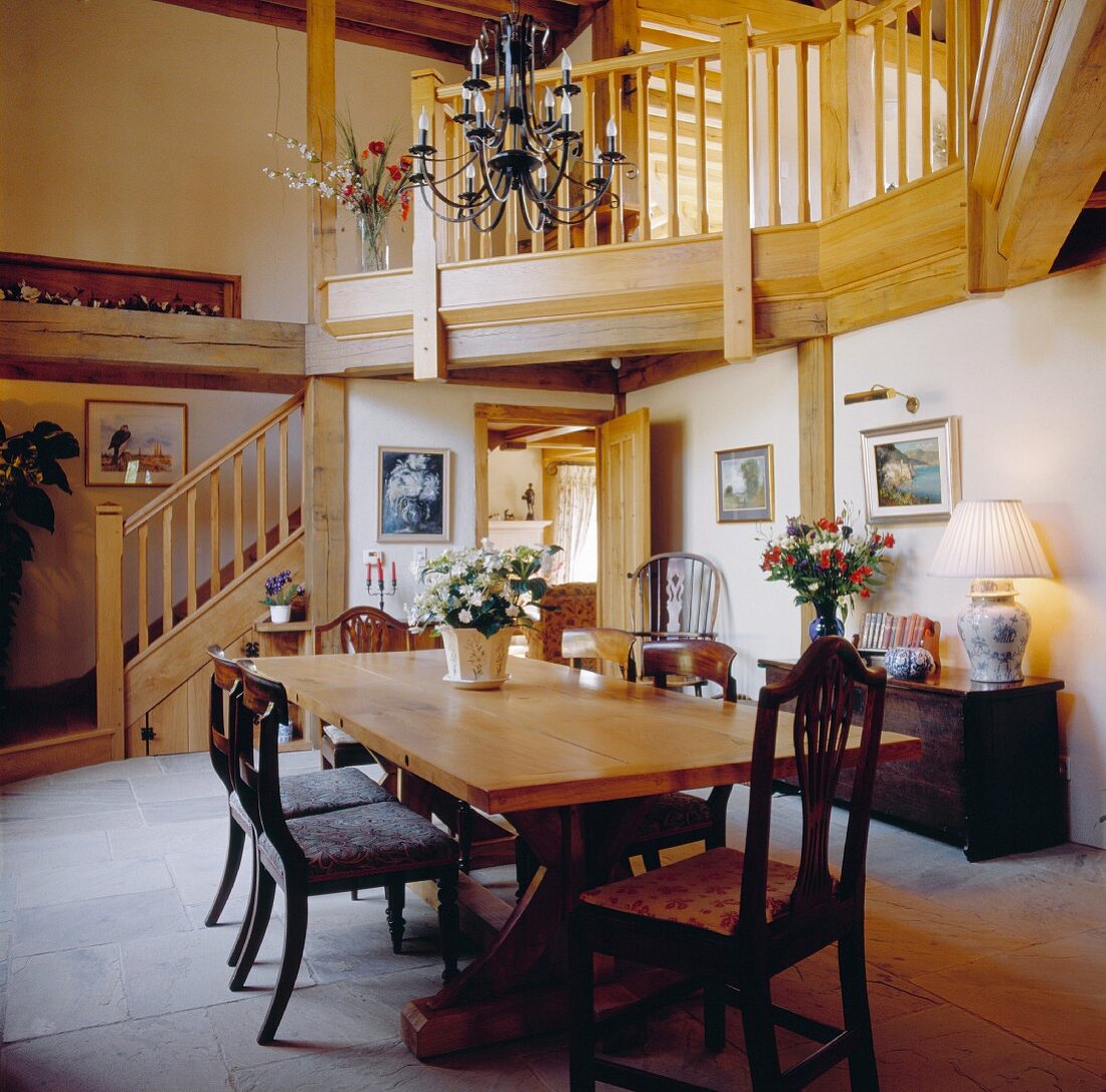 Double-height dining room with rustic wooden staircase and gallery