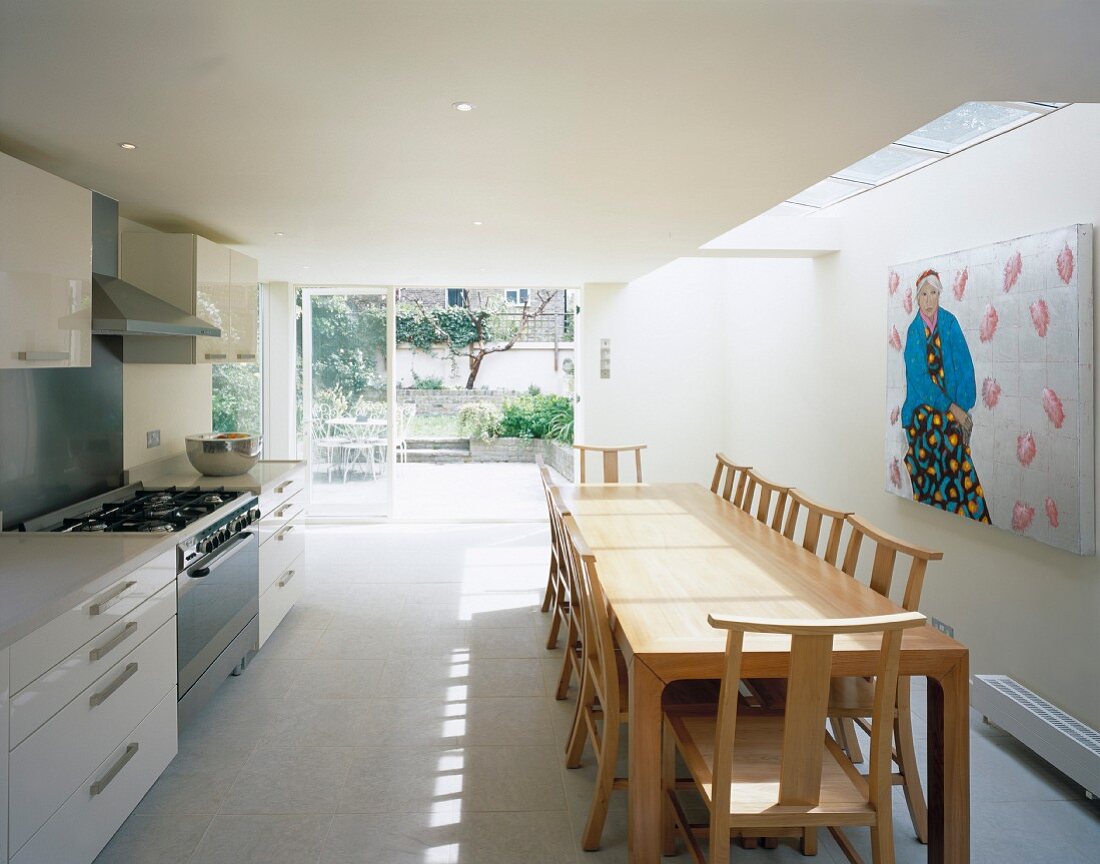 Moderne Wohnküche mit langer Tafel unter Oberlichtfenster