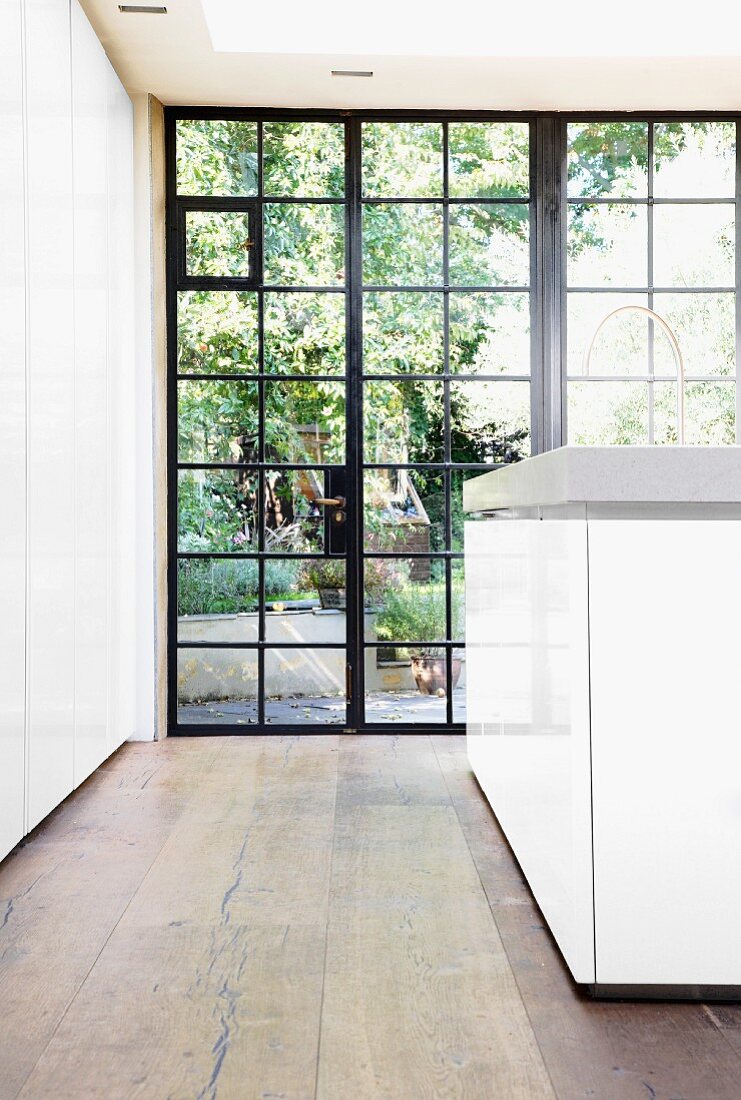 Historische, metallgerahmte Fensterfront und massiver Holzboden in moderner Küche