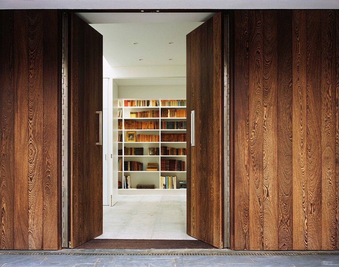 Holzwand mit geöffneter Doppeltür und Blick auf Bücherregal