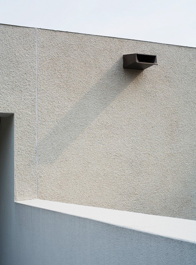 White, plaster facade with overflow pipe for flat-roof drainage