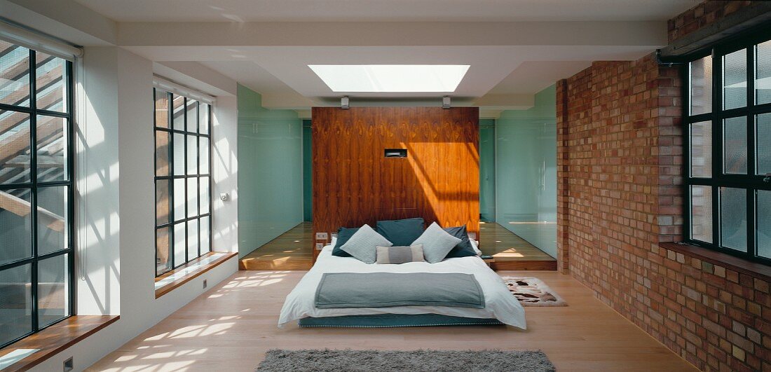 A sunlit loft bedroom with an en suite bathroom behind the double bed