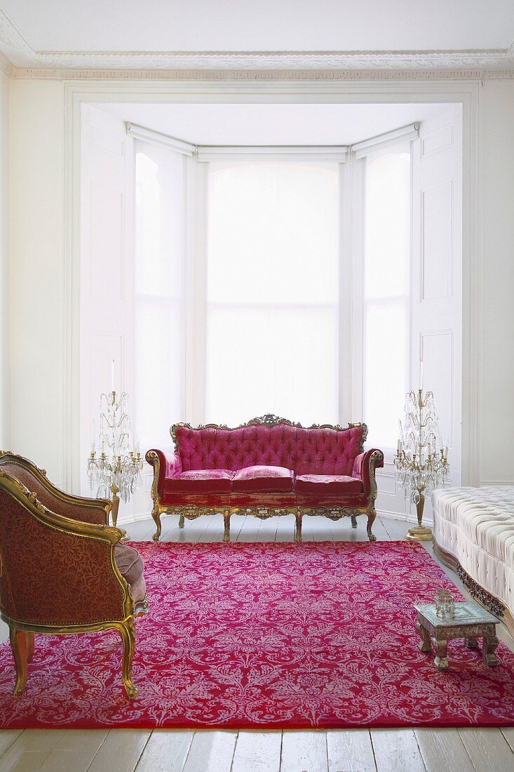 Rokokositzmöbel in Rot und Gold im weissen Wohnraum mit traditionellem Flair