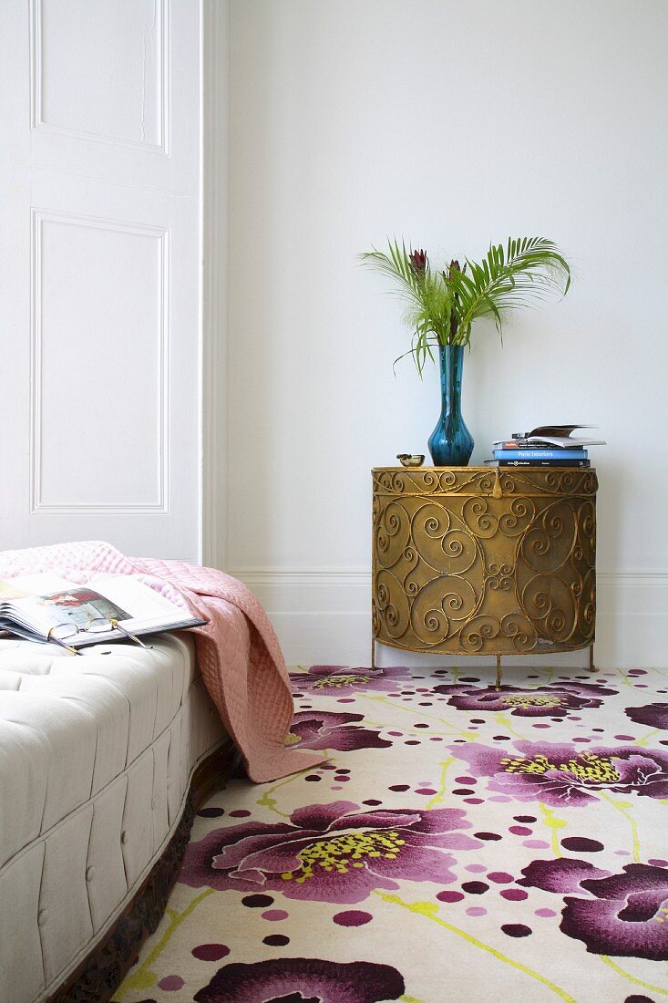 Carpet with floral pattern and semi-circular console cabinet in bronze-coloured metal