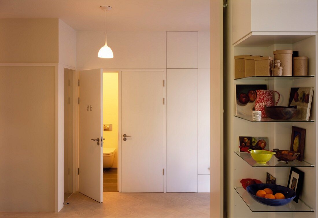 Hallway with shelves built into niche and open toilet door
