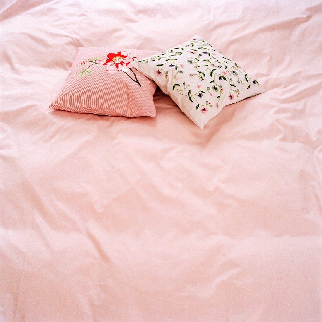 Zwei Zierkissen auf rosa Bettwäsche