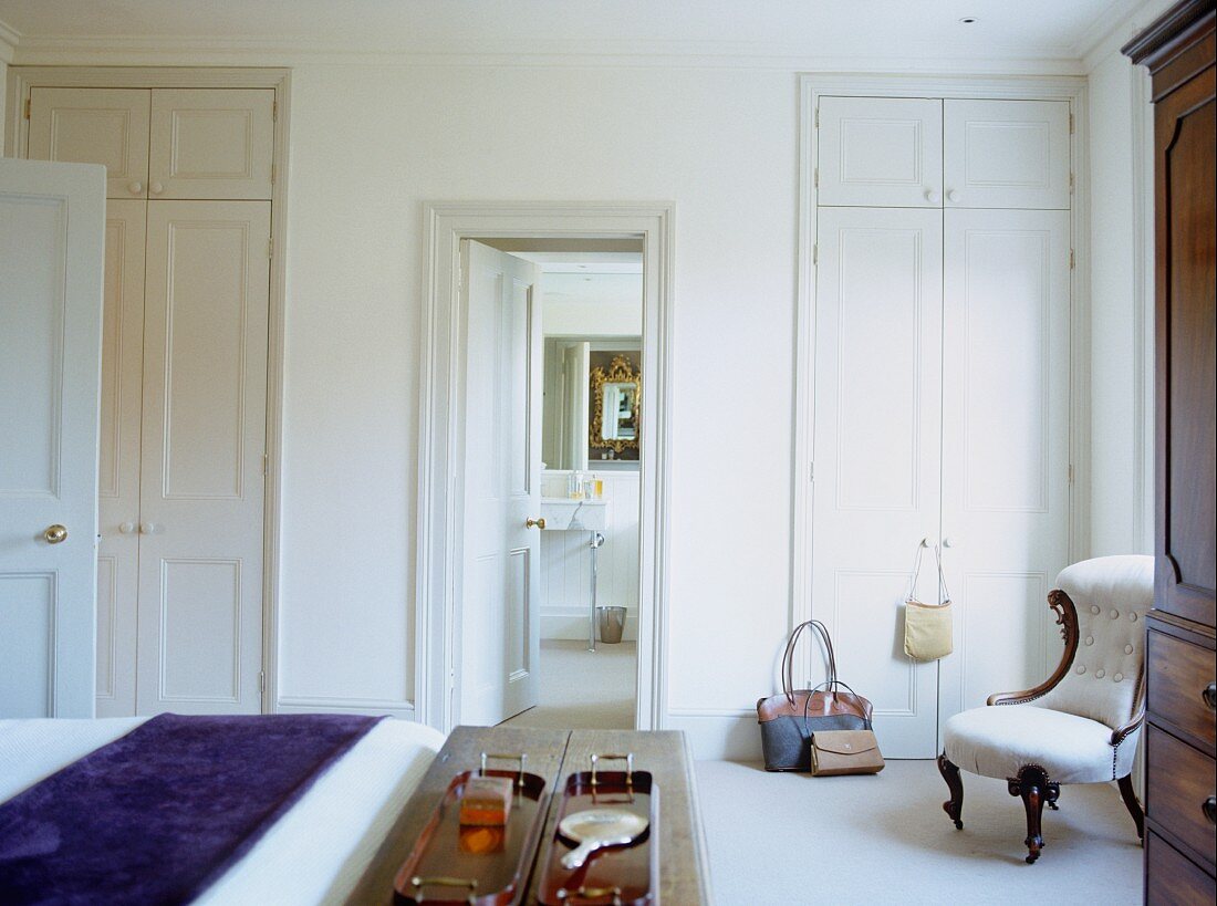 Traditionelles Schlafzimmer in Weiß mit raumhohen Einbauschränken und gepolstertem, romantischem Stuhl