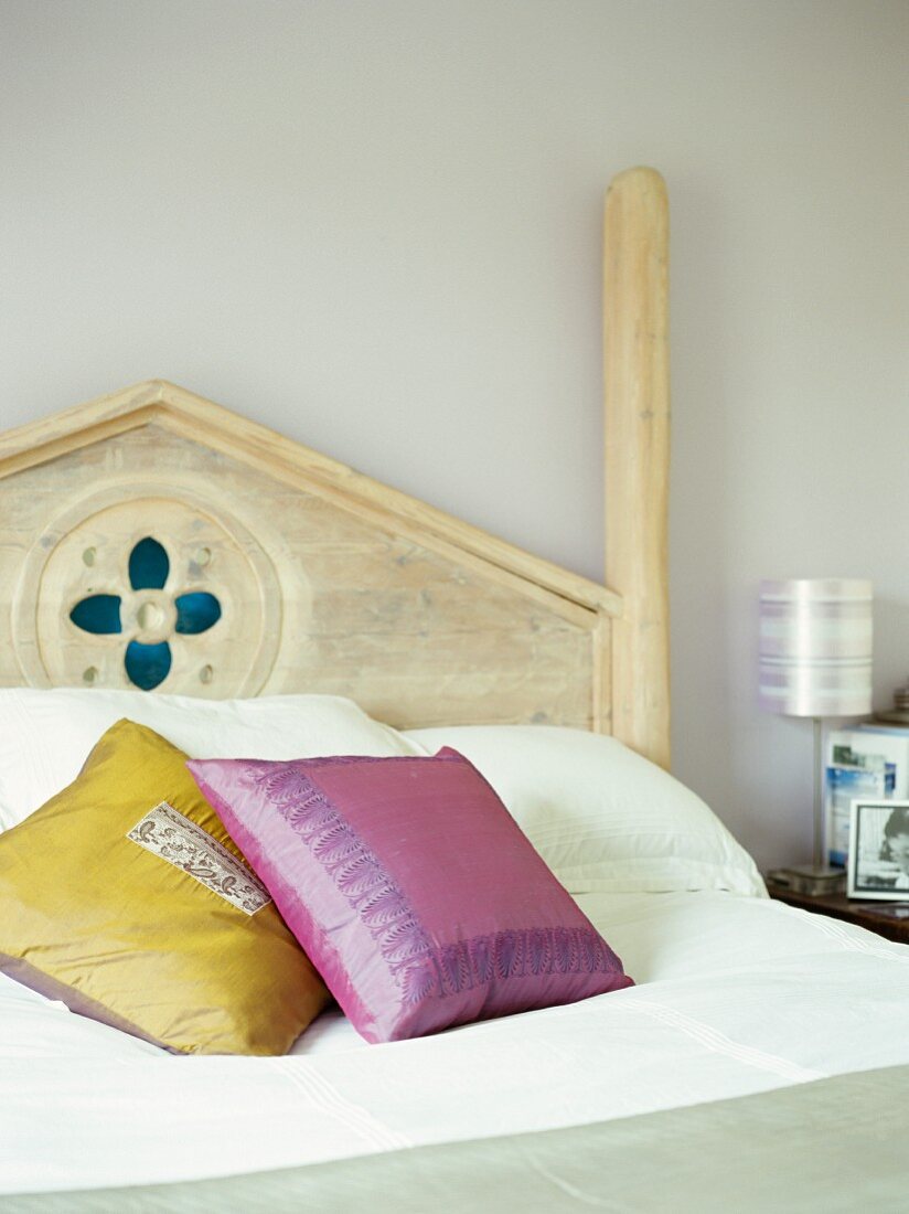 Yellow and violet scatter cushions on romantic wooden bed