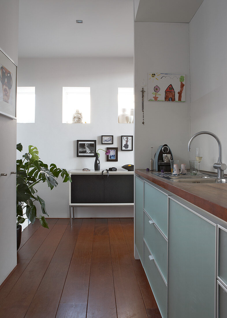 Moderne Küchenzeile in Nische und Blick durch raumhohen Durchgang auf Sideboard