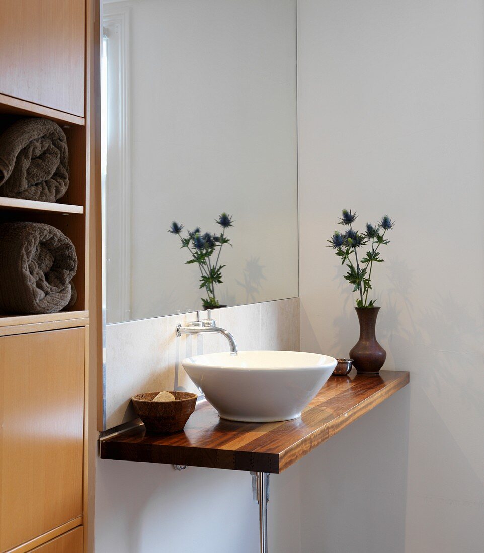 Minimalistischer Waschtisch mit weisser Keramikschüssel auf Holzplatte in Badezimmerecke