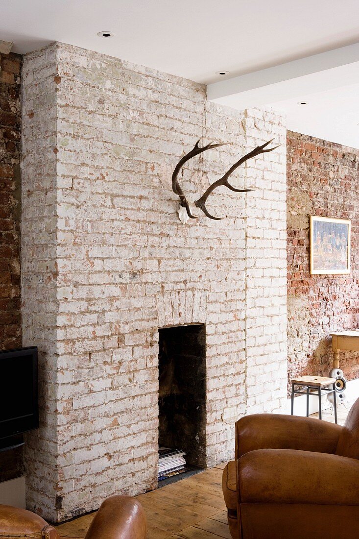 Deer antlers on exposed brick wall above fireplace