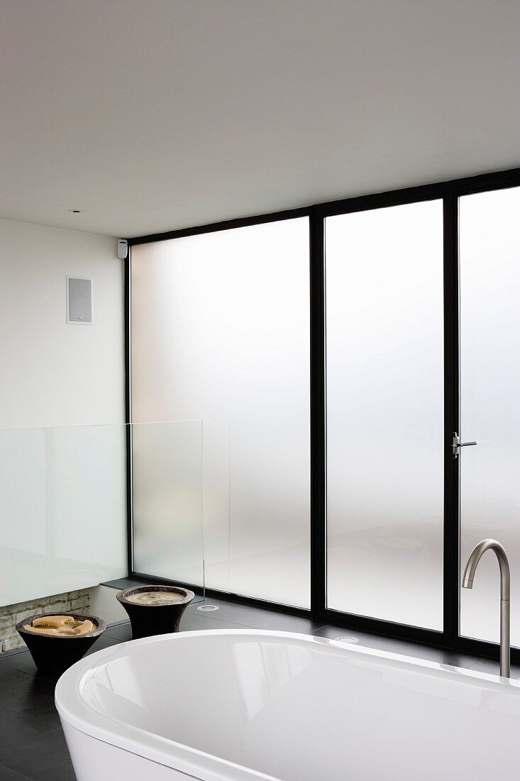 Bathroom with designer bathtub and floor-to-ceiling opaque glass wall