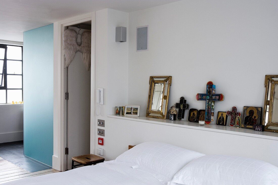 Icons and crosses on shelf at head of bed in modern bedroom