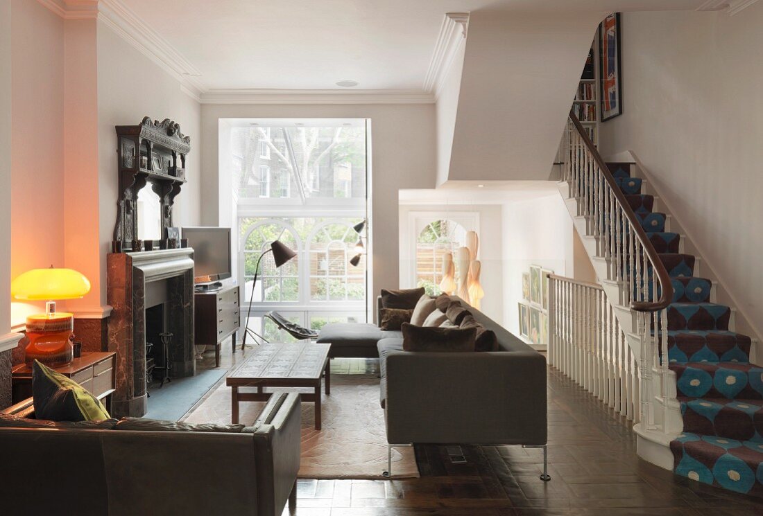 Wohnraum mit Möbeln im Vintagelook und offener Treppe mit gemustertem Teppichläufer