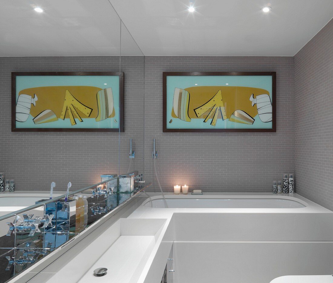 Waschtisch vor verspiegelter Wand und modernes Bild über Badewanne im Designerbad