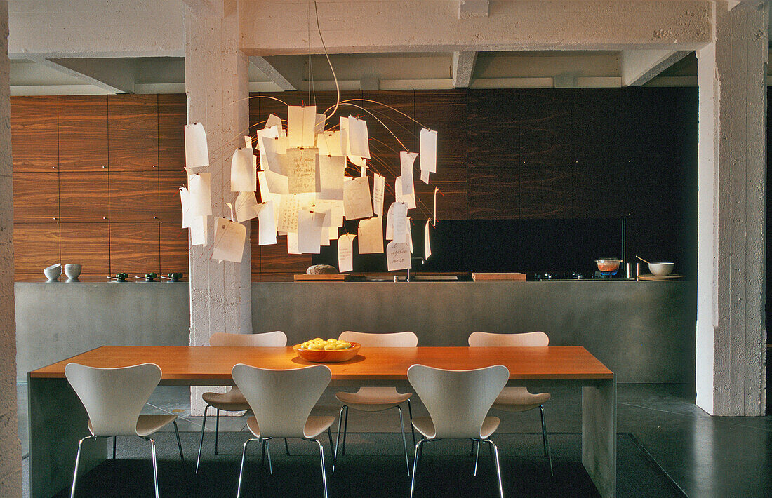Dining table with modern chairs and unusual pendant light in loft flat