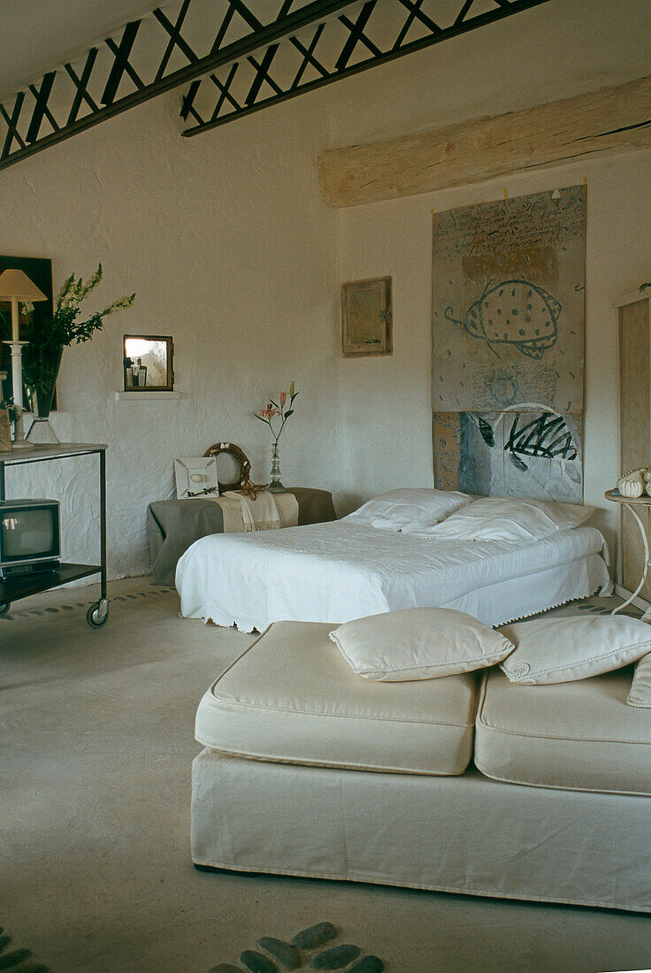 Schlafzimmer mit rustikalen Balken, Kunstwerk und hellen Stoffen