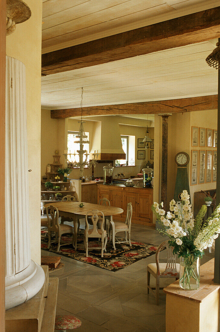 Country-style home with view of dining area and kitchen with wooden beams