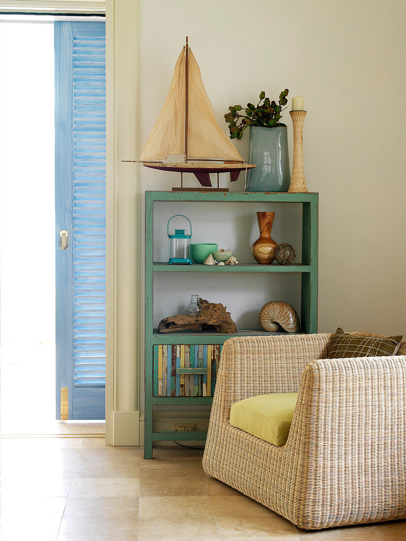 Rattan armchair in front of painted shelves in corner of living room