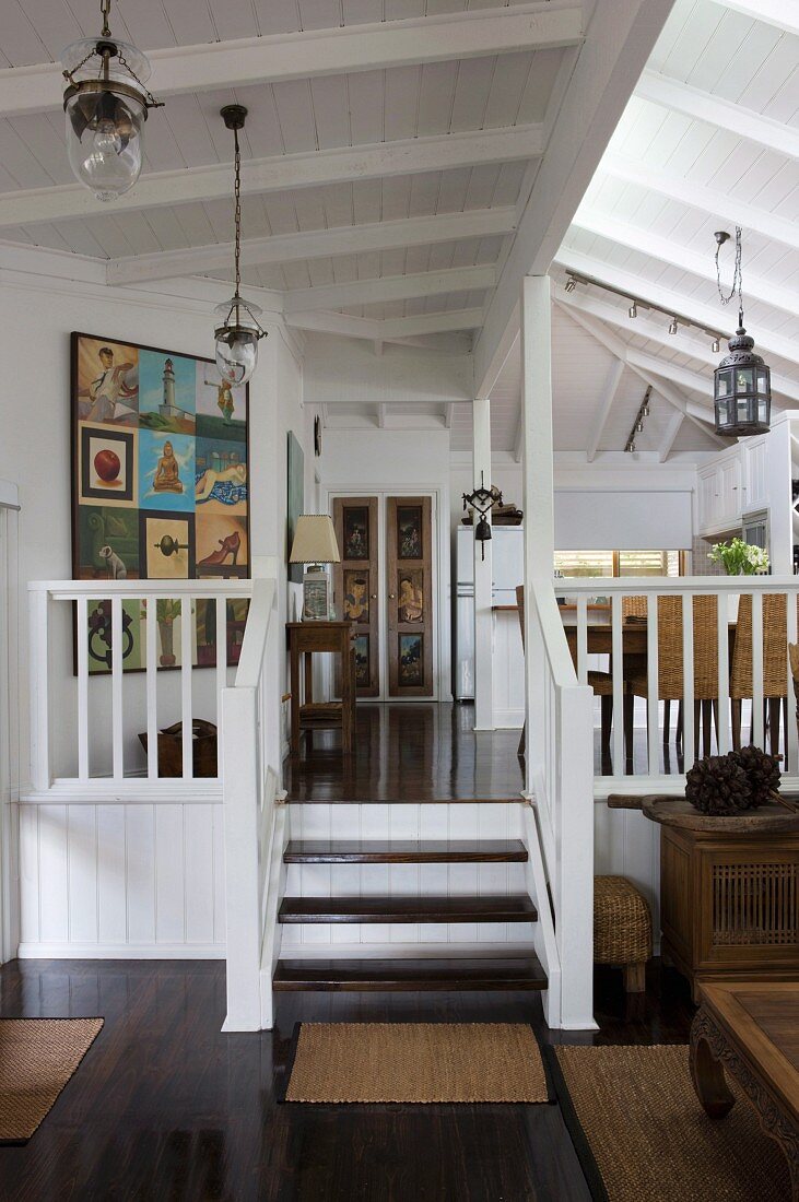 Offener Wohnraum mit Treppe an Empore in ländlichem Wohnhaus mit weisser Holzdecke