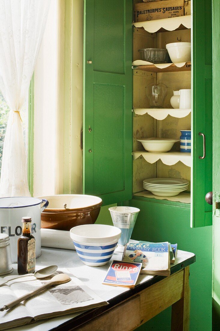 Geschirrschrank aus grün lackiertem Holz mit geöffneten Türen