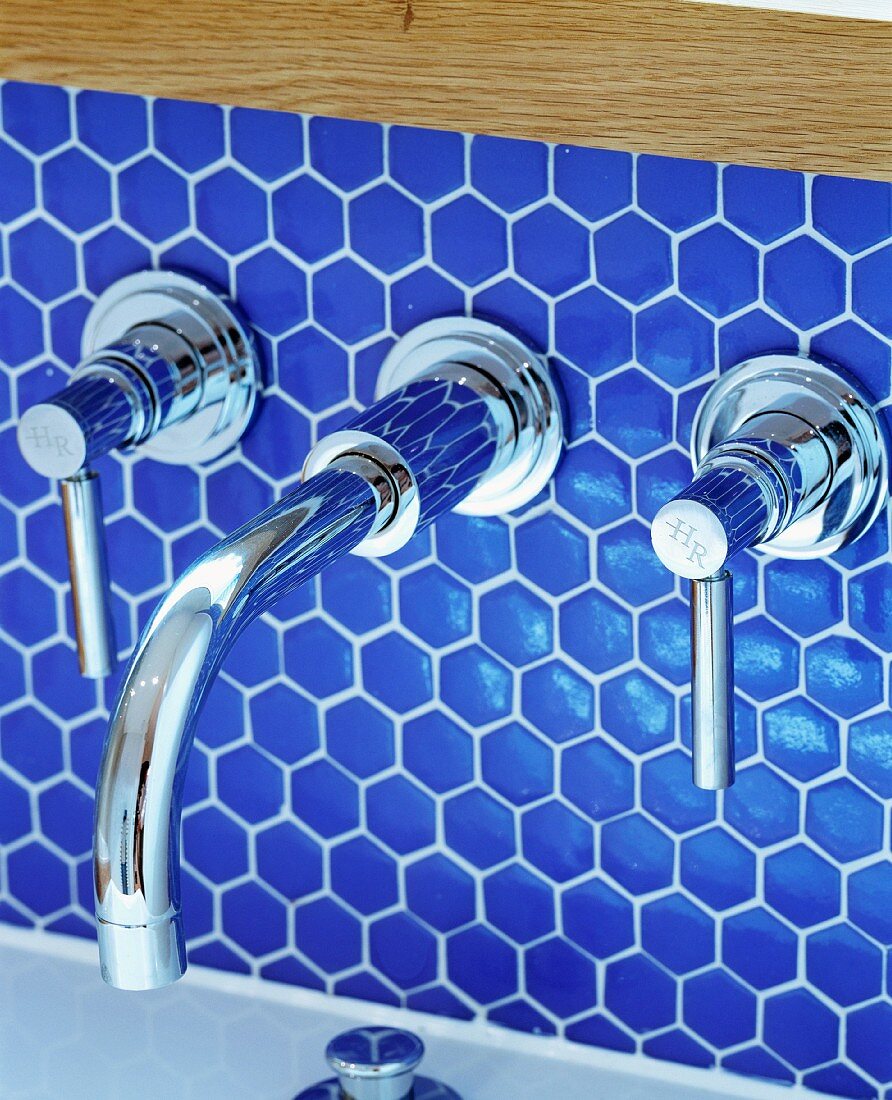 Designer Wandarmatur aus Chrom an blauer Mosaikfliesenwand