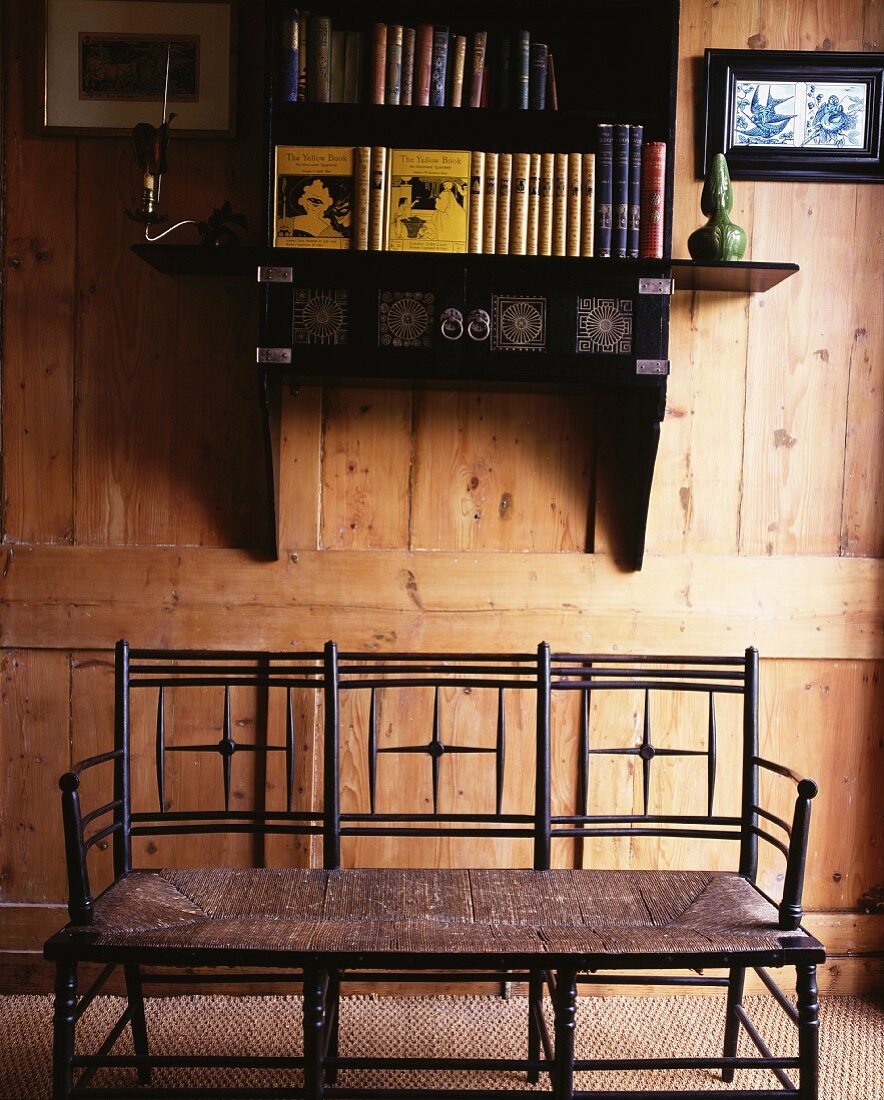 Wooden bench below wall-mounted Oriental shelves on rustic wooden wall