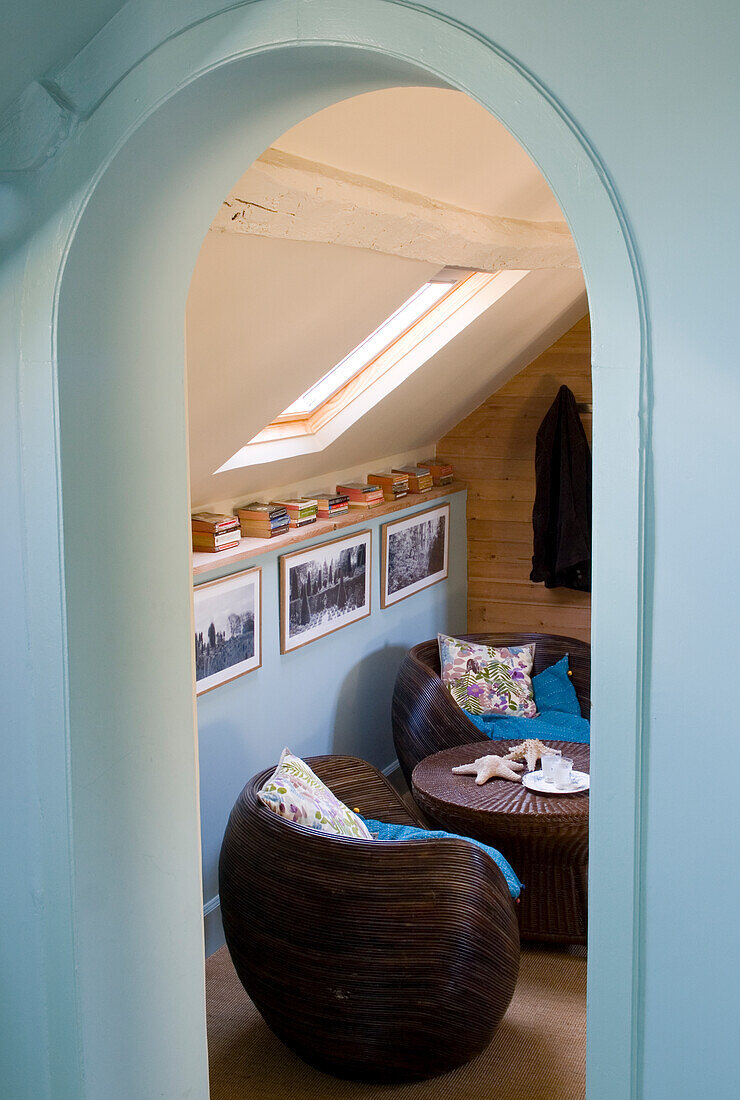 Cosy sitting area under a sloping roof with rattan armchairs