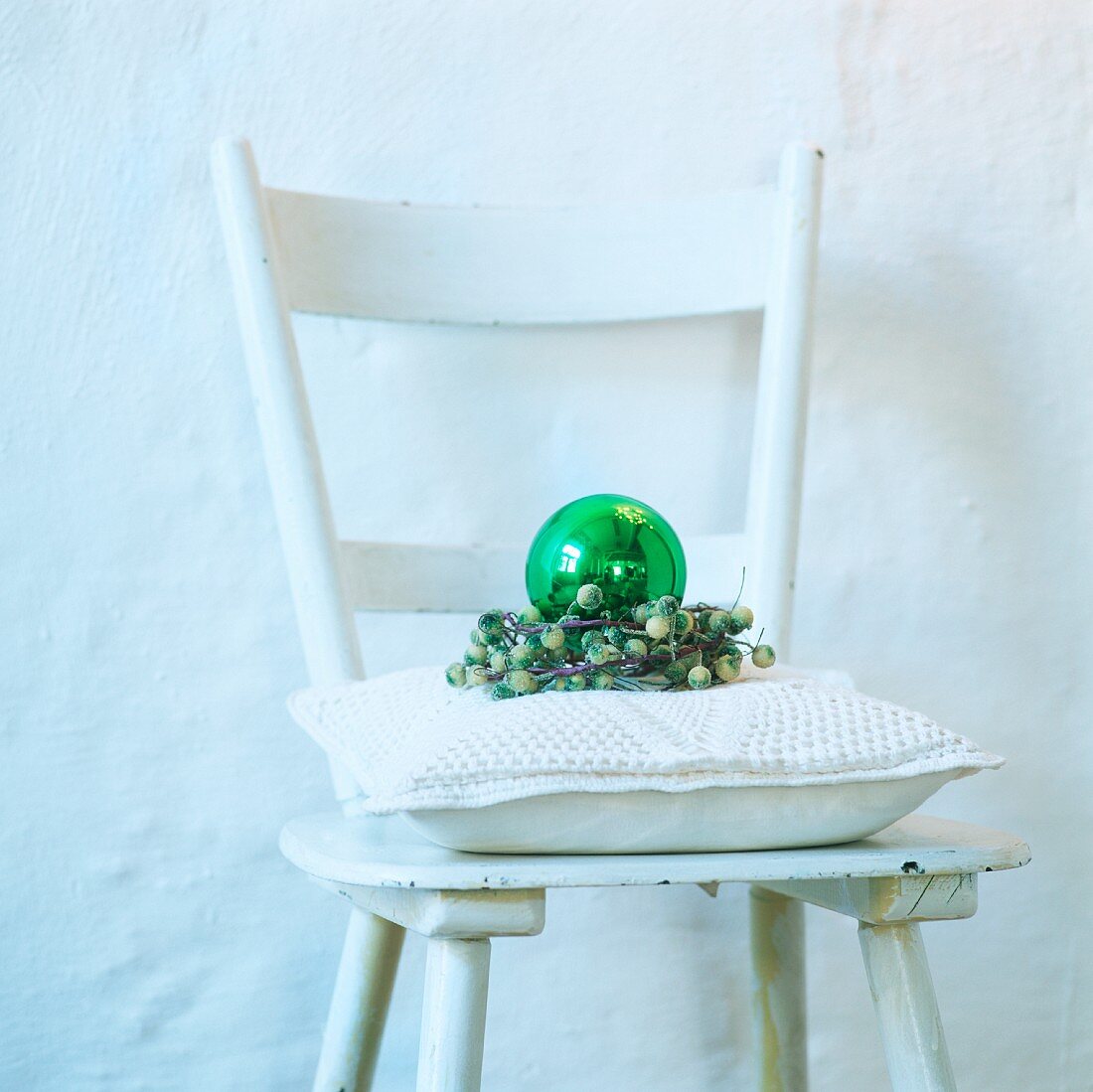 Ein weisser Stuhl mit Kissen und Weihnachtsdeko