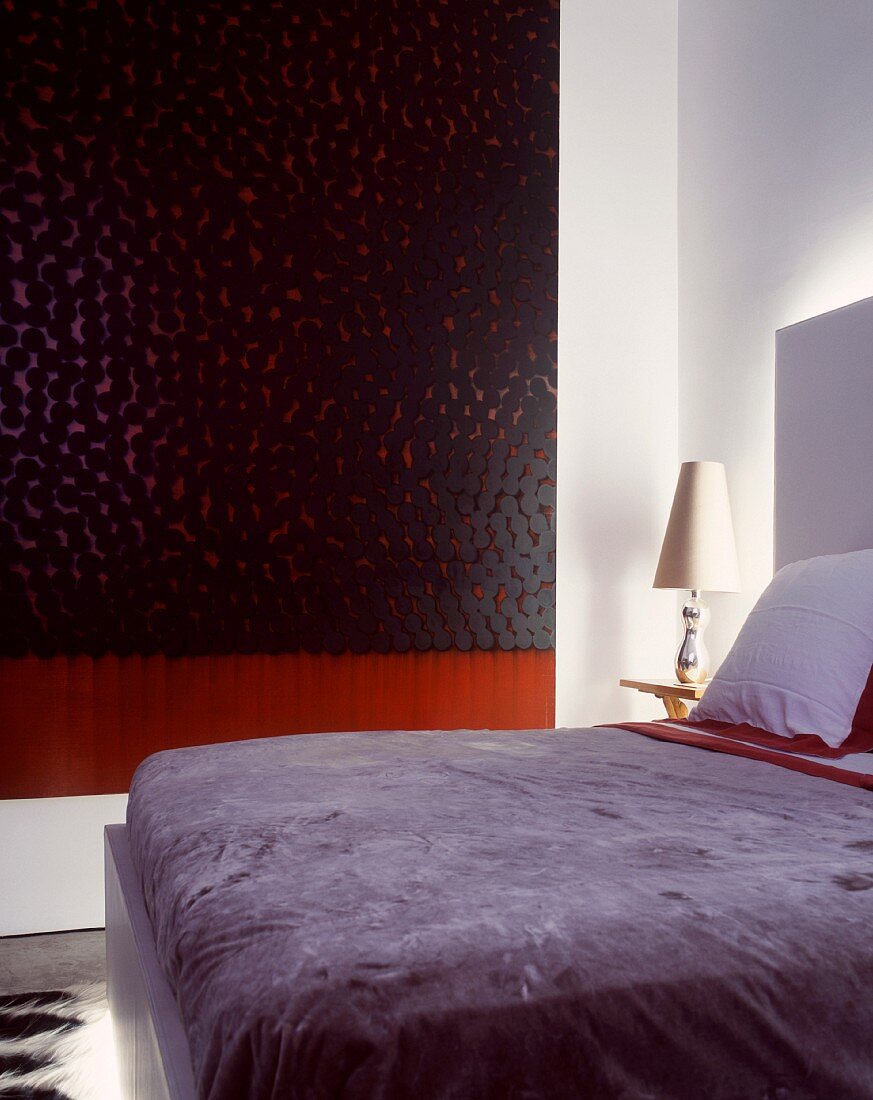Schlichtes Bett im modernen Schlafraum mit Kunstinstallation an Wand